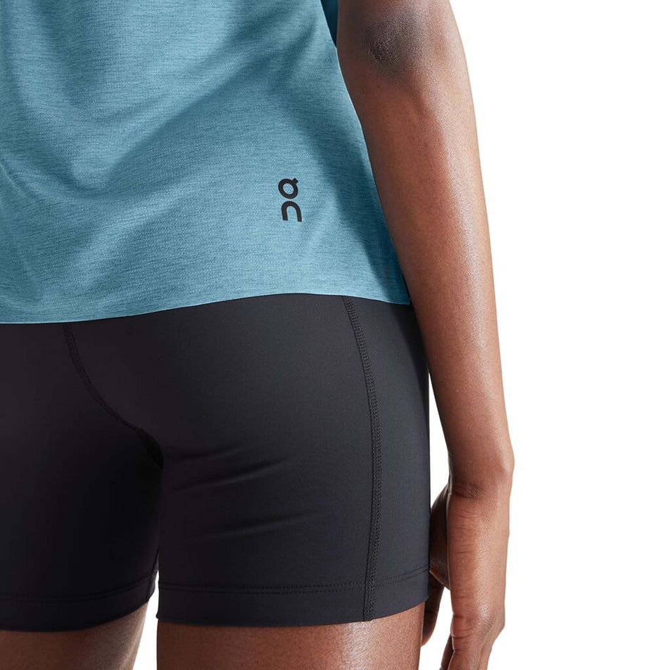 Close-up back view of a model wearing an On Women's Performance T in the Black/Wash colourway. Lower right section of the t-shirt is visible, with the On logo on display. (8002756313250)