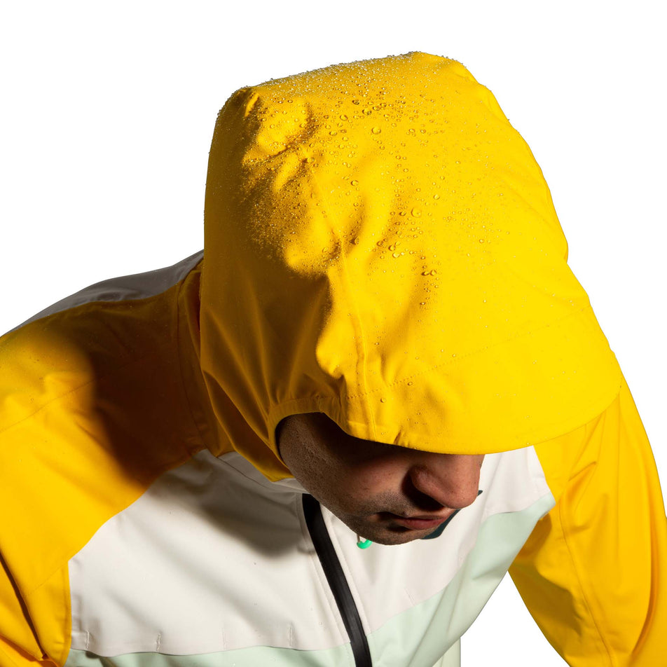 Beads of water sitting on top of the hood of a Brooks Men's High Point Waterproof Jacket. The jacket is being worn by a model.  (8177405821090)