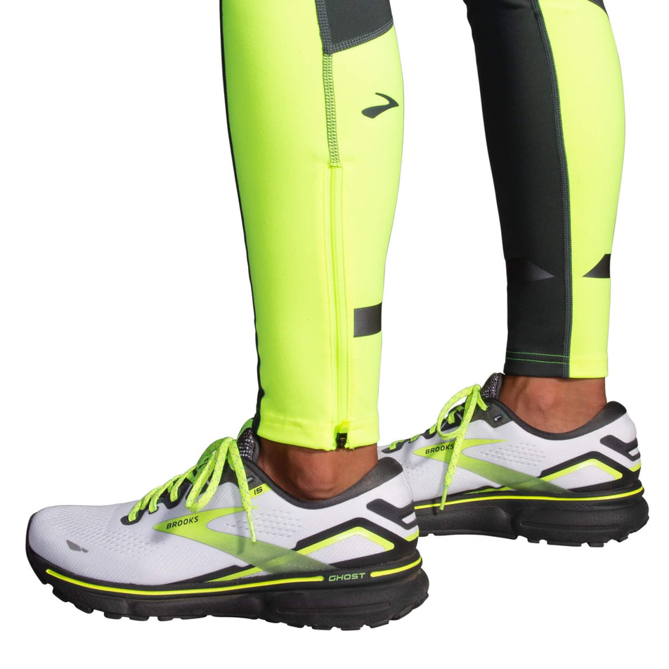 The lower leg section of a pair of Brooks Women's Run Visible Thermal Tights. The tights are being worn by a model who is also wearing Brooks running shoes.  (8065569194146)