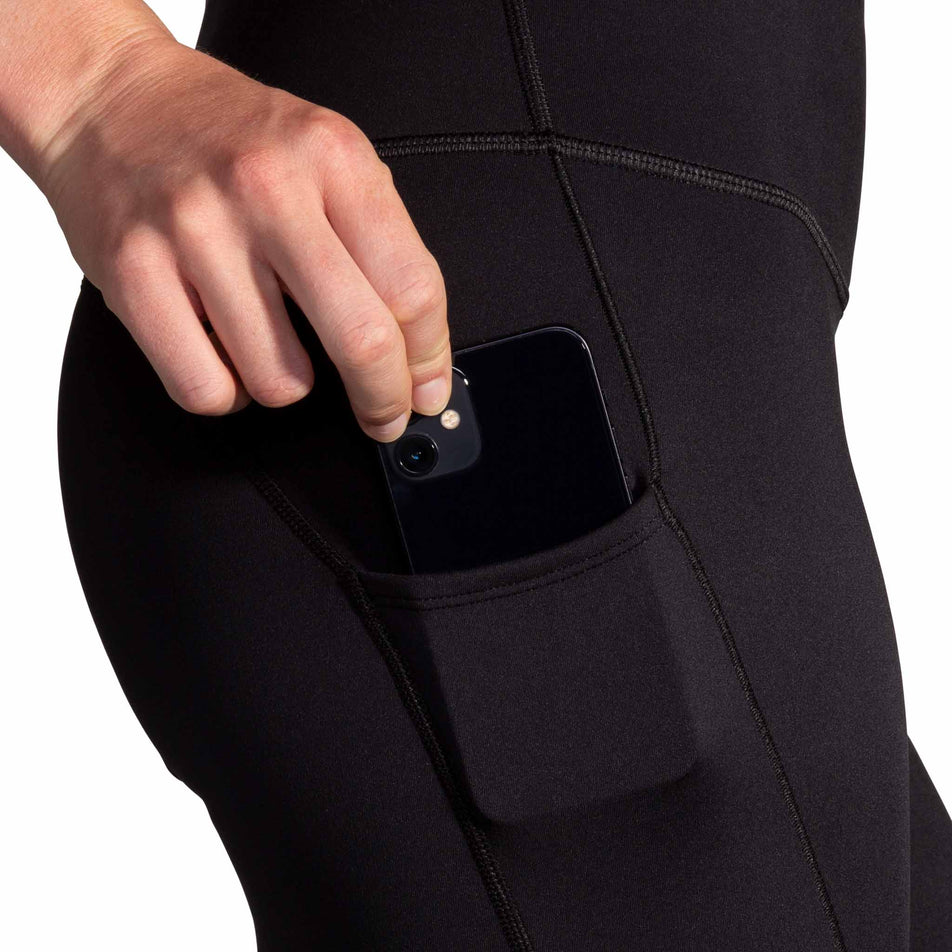 A model demonstrating the drop-in pocket on the side of the Brooks Women's Spark Tight in the Black colourway. (8718911406242)