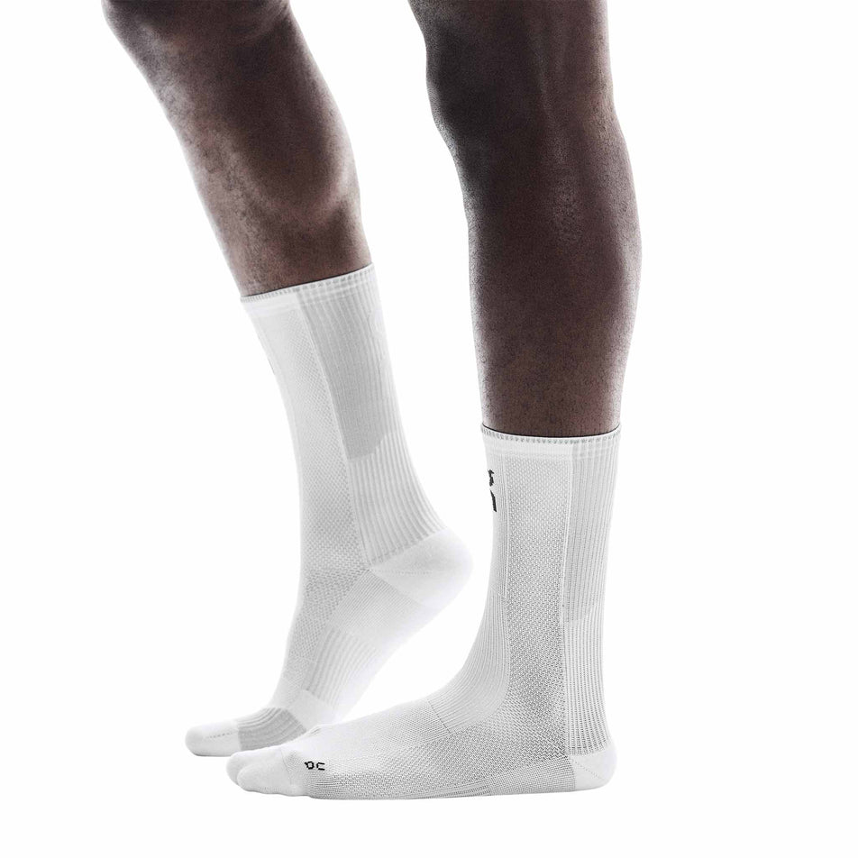 Side view of a model wearing a pair of On Unisex Performance Run Sock High in the White/Glacier colourway. (8717343522978)