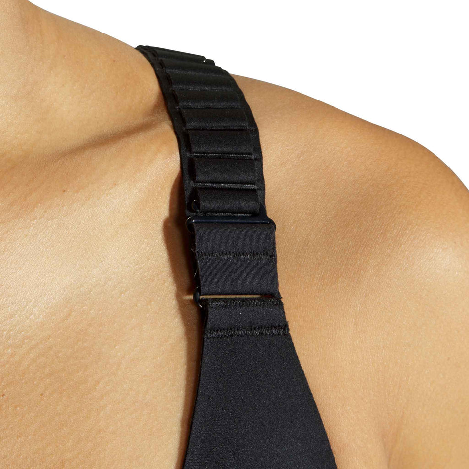 Close-up of an adjustable strap on the front of a Brooks Women's Scoopback 2.0 Sports Bra in the Black colourway. Bra is being worn by a model. (8636841099426)