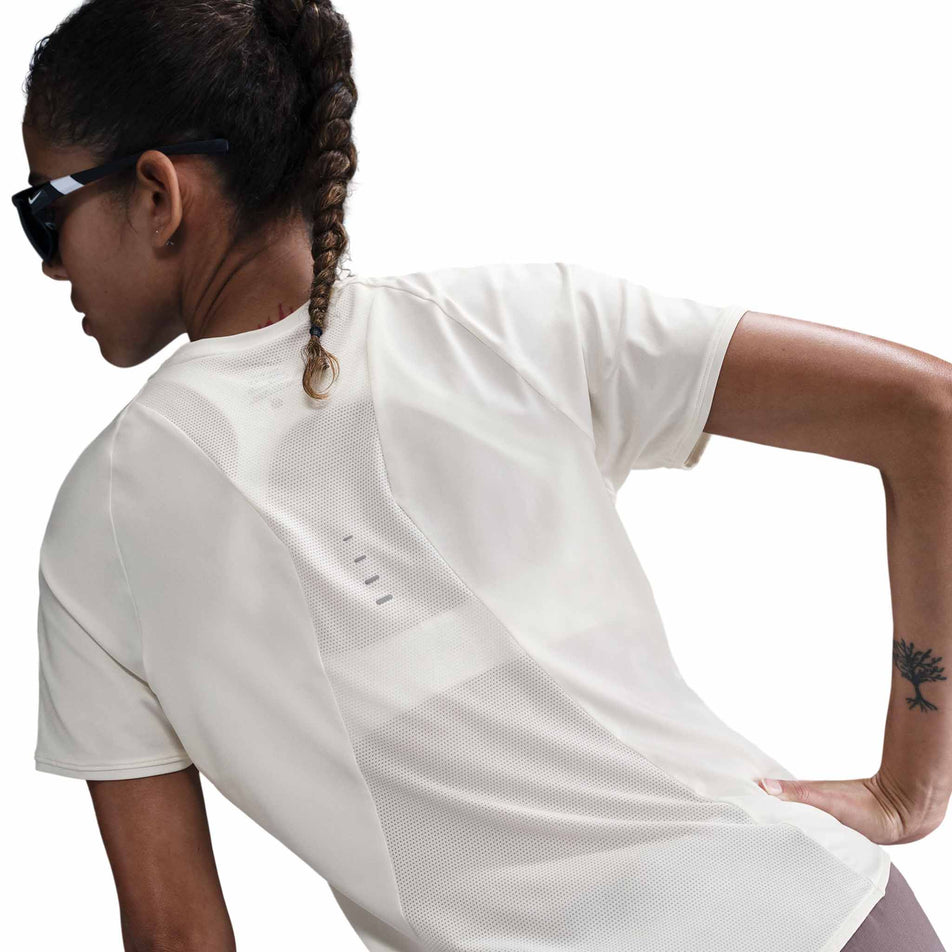 Back view of a model wearing the Nike Women's Swift Dri-FIT Short-Sleeve Running Top in the Sail/Reflective Silver colourway. (8692848984226)
