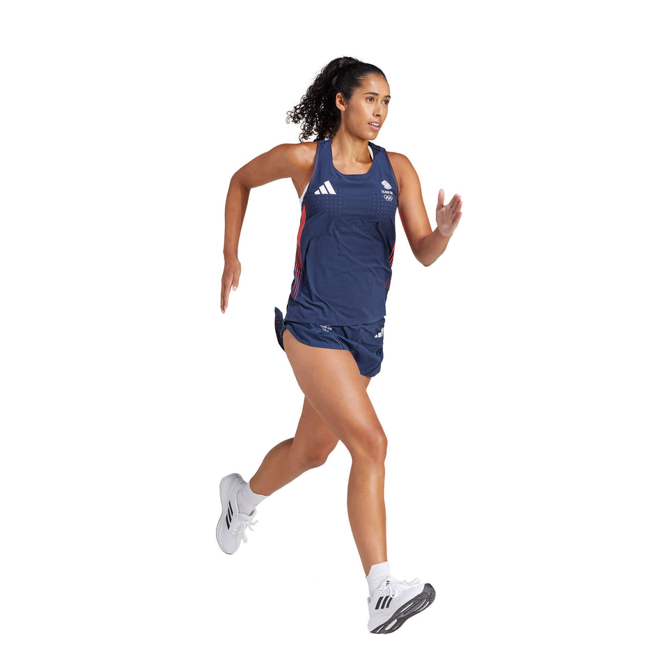 Angled front view of a model wearing a pair of adidas Women's Team GB Adizero Running Split Shorts in the Legend Ink colourway. Model is also wearing a singlet, socks and shoes, and is in a running pose. (8323635052706)