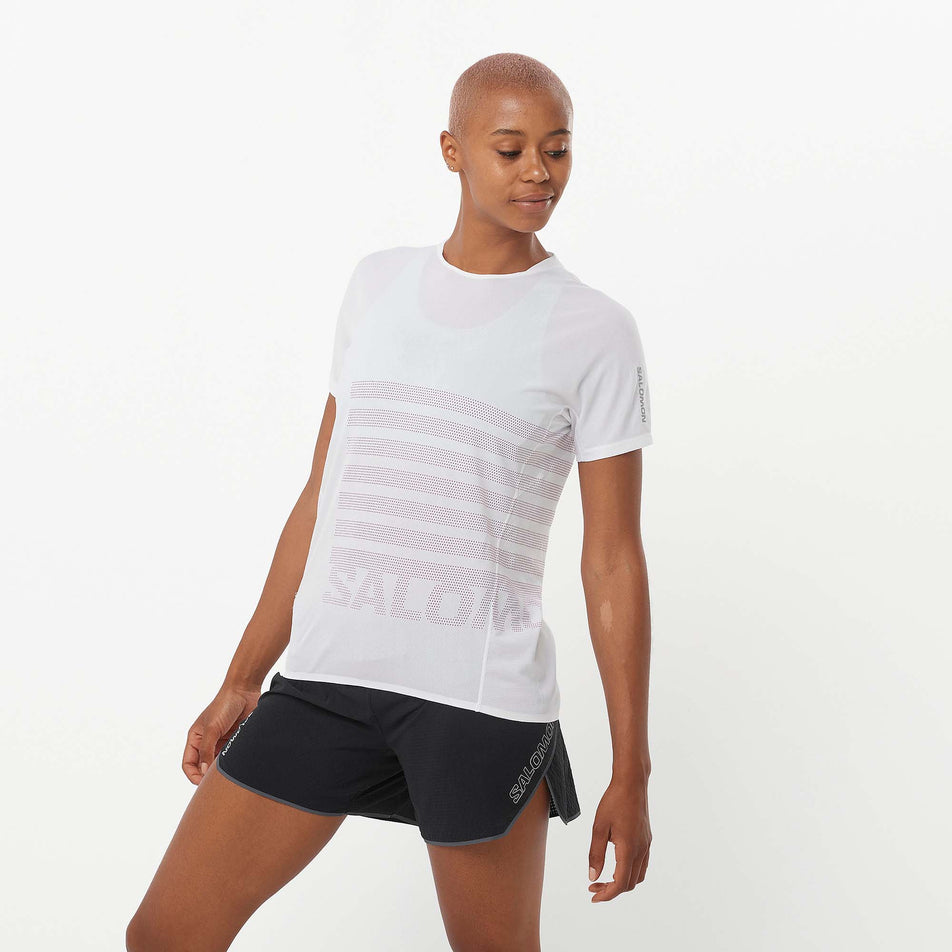 Front view of a model wearing a Salomon Women's Sense Aero GFX Short Sleeve Tee in the White/Beetroot Purple colourway. Model is also wearing Salomon running shorts. (8157870850210)