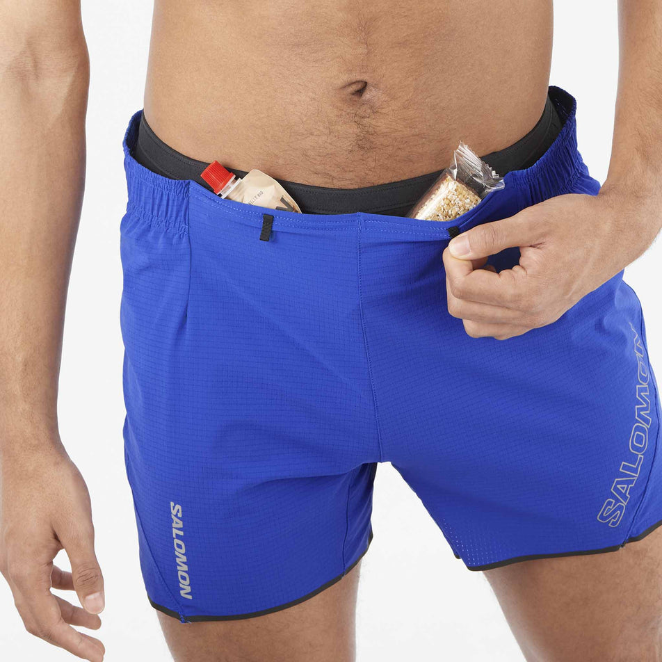 Front view of a model demonstrating that energy gels can be stored in the front stretch pockets on a pair of Salomon Men's Sense Aero 5