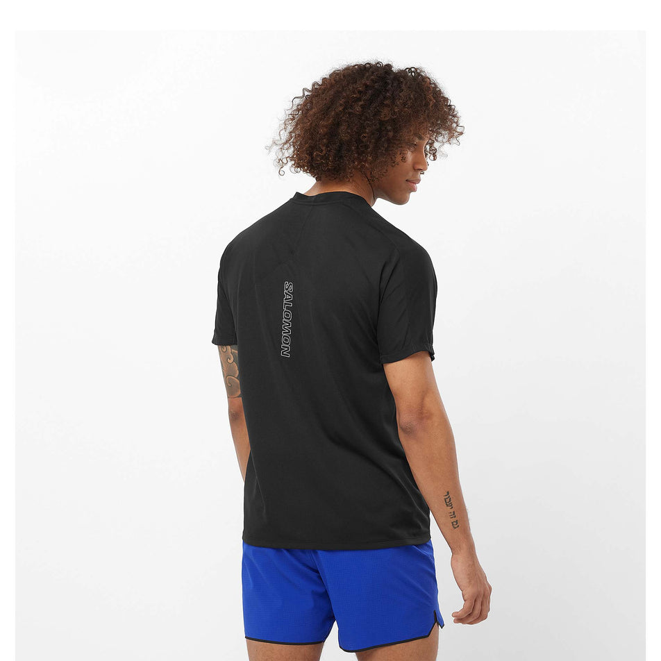 Back view of a model wearing a Salomon Men's Sense Aero Short Sleeve T-Shirt in the Deep Black colourway. Model is also wearing shorts. (8466523029666)