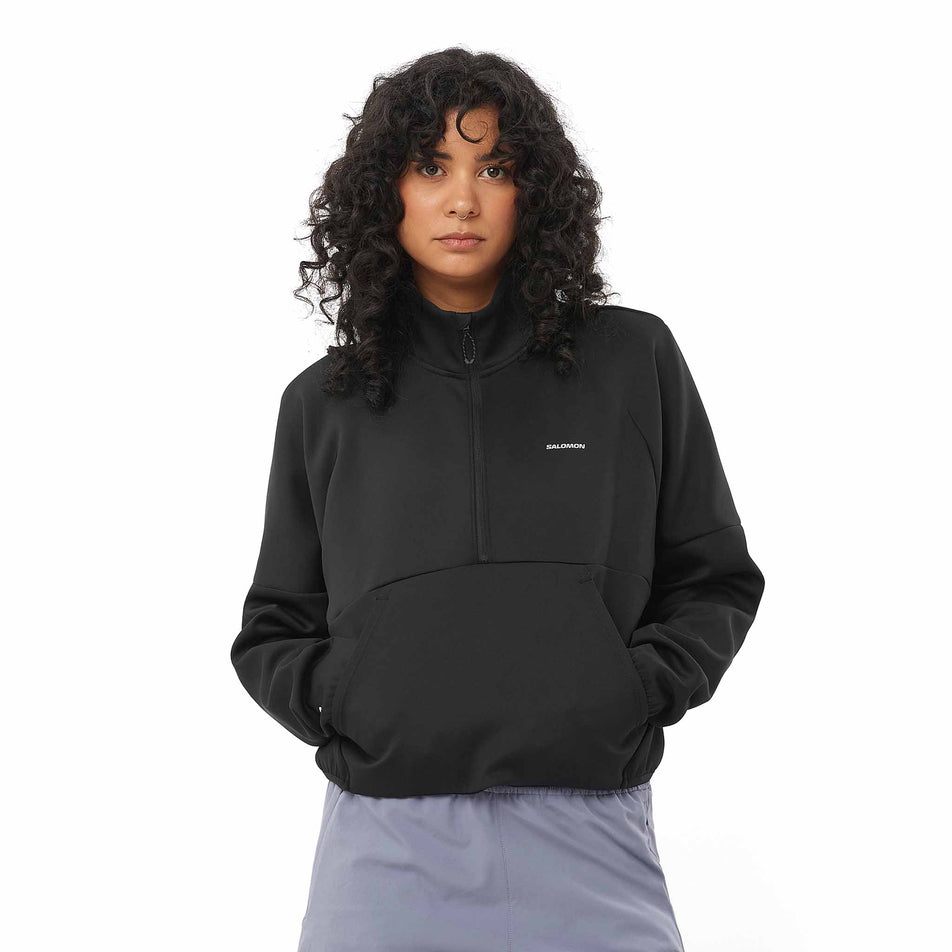 Front view of a model wearing the Salomon Women's SHKout Half Zip Midlayer in the Deep Black colourway. (8575544721570)