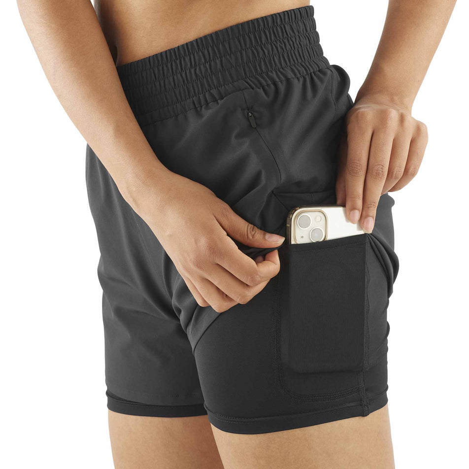 A model demonstrating the stash pocket on the liner of the Salomon Women's SHKout Core 2in1 4
