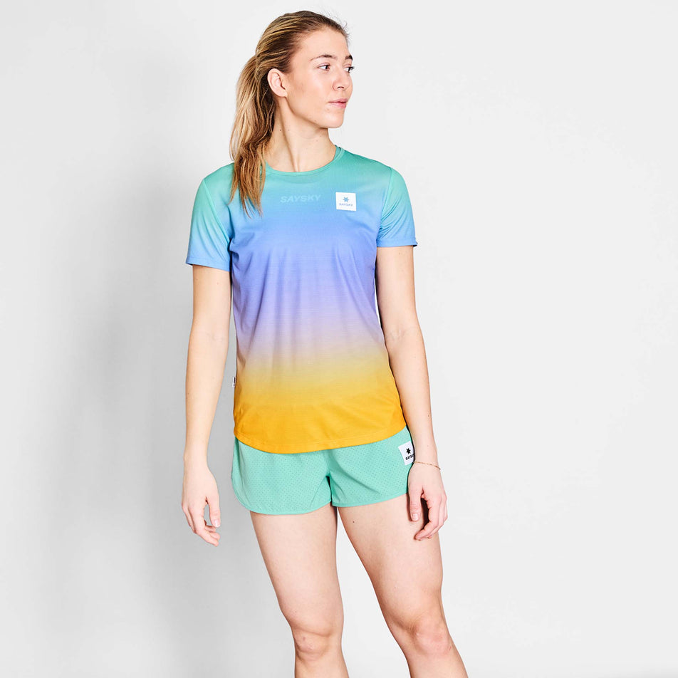 Front view of a model wearing the SAYSKY Women's Drip Dye Flow T-Shirt in the Purple AOP colourway. Model is also wearing shorts. (8675475030178)