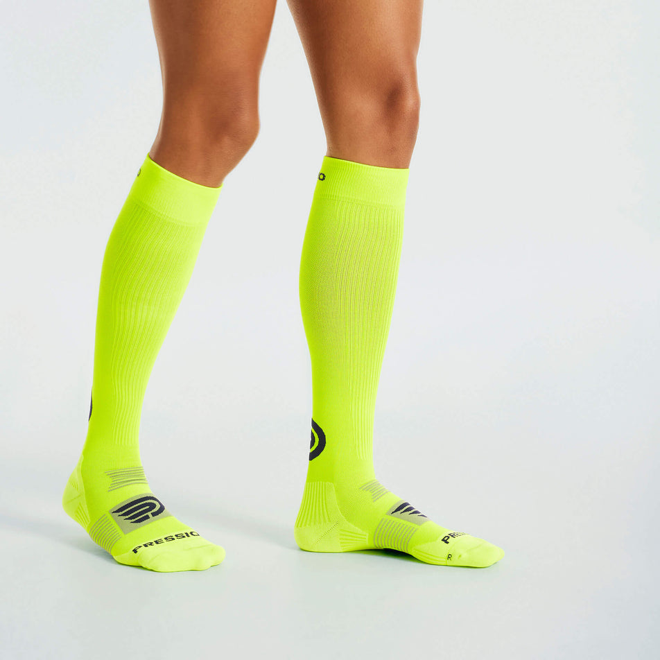 Side view of a model wearing the Pressio Unisex EQ Compression Socks in the Yellow/Navy colourway. (8341599781026)
