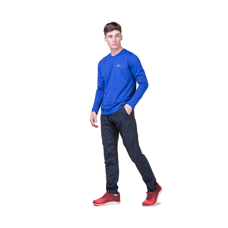 Front view of a model wearing a Ronhill Men's Core L/S Tee in the Dark Cobalt/Bright White colourway. Model is also wearing running trousers and running shoes.
(8468452049058)
