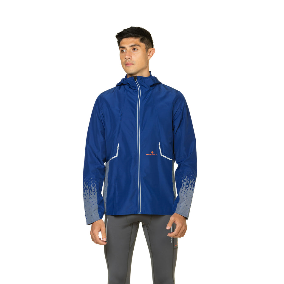 Front view of a model wearing a Ronhill Men's Tech Reflect Jacket in the Ocean/Reflect colourway. Model is also wearing leggings. (8469614395554)