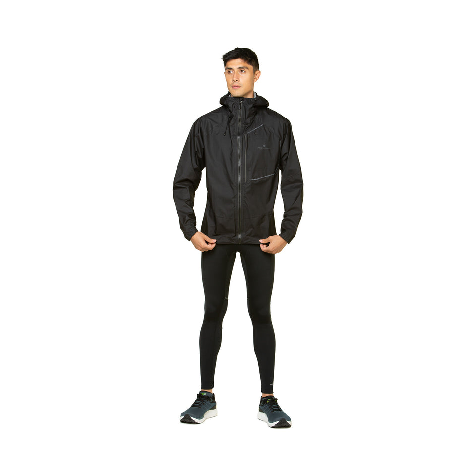 Front view of a model wearing the Ronhill Men's Tech Fortify Jacket in the All Black colourway. Model is also wearing shoes and a top. (8490250829986)