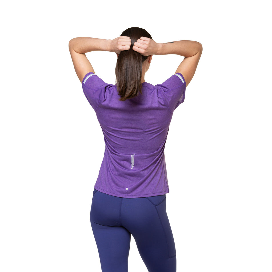 Back view of a model wearing a Ronhill Women's Tech Reflect S/S Tee in the Regal Purple/Reflect colourway. Model is also wearing tights. (8489750397090)
