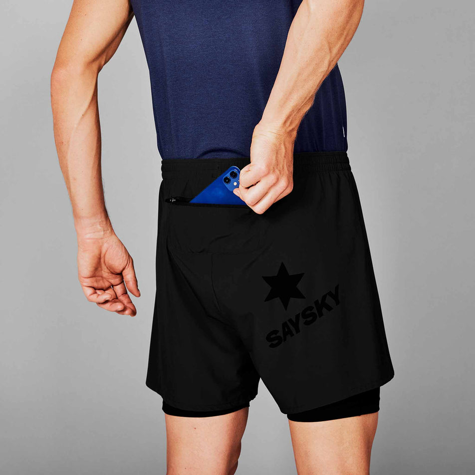 A model demonstrating that a phone can be stored in the zipped back pocket of the SAYSKY Men's 2 In 1 Pace Shorts 5